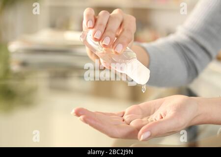 Nahaufnahme der Frau, die die Hand mit dem Desinfektionsgel des Desinfektionsmittels desinfiziert, um Ansteckungen zu verhindern, die zu Hause auf einem Schreibtisch sitzen Stockfoto