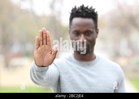 Vorderansicht Porträt eines wütenden schwarzen Mannes Gesturenanschlag zeigt Handfläche im Freien in einem Park Stockfoto