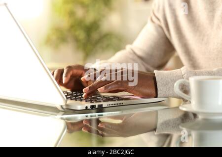 Nahaufnahme der schwarzen Hände, die auf einem Laptop tippen, der zu Hause auf einem Schreibtisch sitzt Stockfoto
