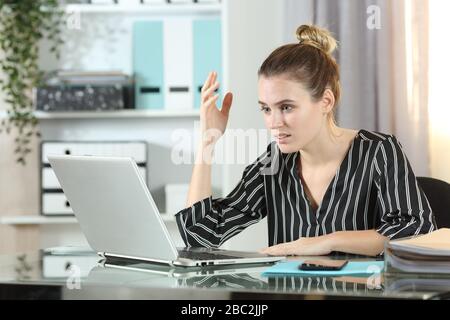 Frustrierte Unternehmerin mit Laptop, die sich auf einem Schreibtisch im Büro beschwert Stockfoto