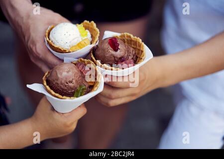 Nahaufnahmen von drei Händen, die Waffelkegel von Eis enthalten Stockfoto