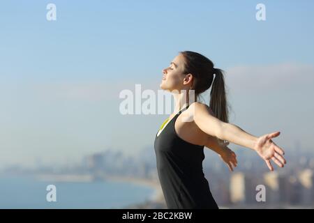 Seitenansicht Porträt eines entspannten Läufers, der an einem sonnigen Tag frische Luft in den Randgebieten der Stadt atmet Stockfoto