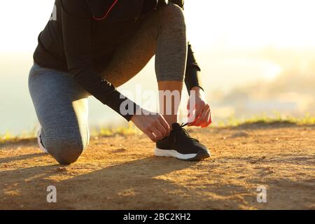 Die Läuferin händet bei Sonnenuntergang Schnürsenkel von Schuhen auf dem Boden Stockfoto