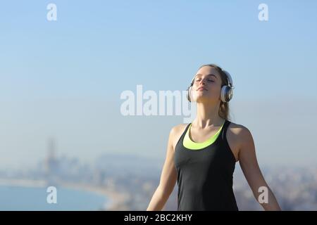 Entspannter Läufer mit Kopfhörern, der frische Luft in den Außenbereichen der Stadt atmet Stockfoto