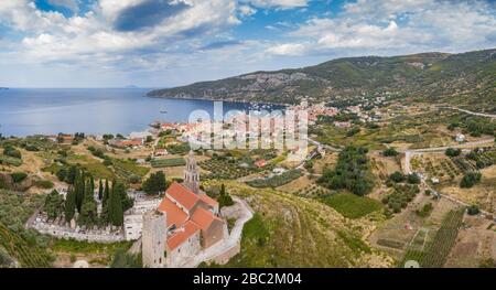 Luftpanorama über die Kathedrale St.Nicholas in der Stadt Komiza - eine der zahlreichen Hafenstädte in Kroatien, orangefarbene Dächer von Häusern, Picturisque-Bucht Stockfoto