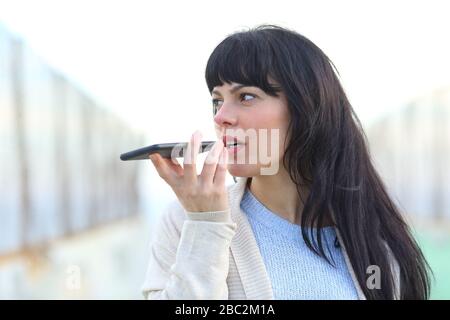 Erwachsene Frau, die mit Spracherkennung auf dem Handy auf der Straße Audio aufzeichnet Stockfoto