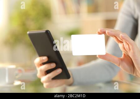 Nahaufnahme der Frau mit dem Smartphone, das auf einem Schreibtisch zu Hause eine leere Kreditkarte anzeigt Stockfoto