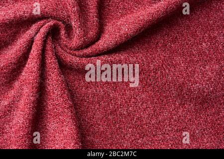 Nahaufnahme roter Struktur aus Wollgestrickstoff. Muster aus rot zerknittertem Stoff. Hochwertige Makrofotografie. Stockfoto