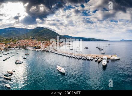 Luftpanorama über die Stadt Komiza - eine der zahlreichen Hafenstädte in Kroatien, ist eine Menge Segelboote einer Regatta, orangefarbene Dächer von Häusern, ein Stockfoto