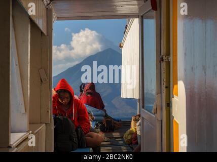 3. November 2019 Larantuka, Flores, Indonesien: Die Einheimischen ruhen auf einem Fährschiff zwischen Leoleba und Larantuka. Mandiri Vulkan in der Ferne Stockfoto