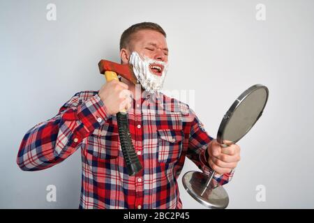 Man rasiert mit einer Axt auf weißem Hintergrund Stockfoto