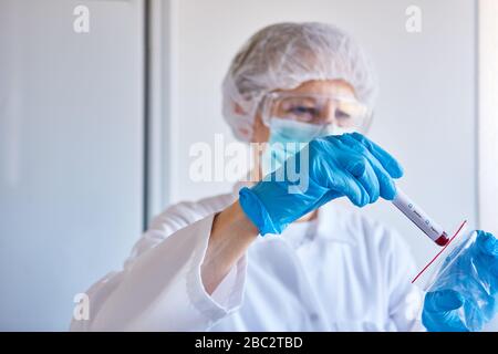 Laborforscher mit Blutprobe von Covid-19-Patienten arbeitet an einem Coronavirus-Impfstoff Stockfoto