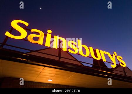 Sainsbury's Supermarkt-Schild nachts/abends mit hellblauem Nachthimmel, Mond und schwachen Sternen. GROSSBRITANNIEN (116) Stockfoto