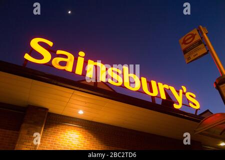 Sainsbury's Supermarkt-Schild nachts/abends mit hellblauem Nachthimmel, Mond und schwachen Sternen. GROSSBRITANNIEN (116) Stockfoto