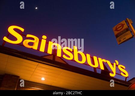 Sainsbury's Supermarkt-Schild nachts/abends mit hellblauem Nachthimmel, Mond und schwachen Sternen. GROSSBRITANNIEN (116) Stockfoto