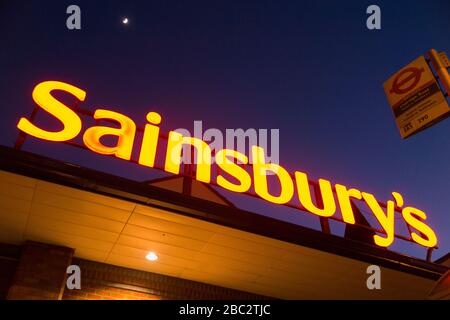 Sainsbury's Supermarkt-Schild nachts/abends mit hellblauem Nachthimmel, Mond und schwachen Sternen. GROSSBRITANNIEN (116) Stockfoto