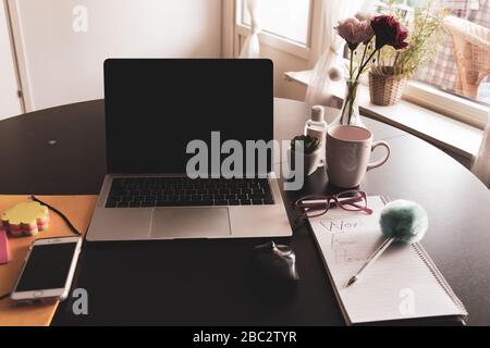 Arbeiten vom Heimkonzept mit Laptop, Kaffeetasse, Maus und Notizblock mit Heimarbeit auf einem Esstisch, Schweden, Gothenburg Stockfoto