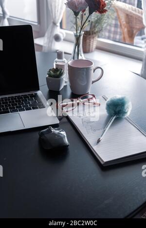 Arbeiten von zu Hause aus mit einer Laptop-Tastatur mit Kaffeetasse, Maus und Notizblock mit Heimarbeit auf einem Esstisch, Schweden, Gothenburg Stockfoto