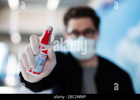 Ein Mann mit einer Atemmaske hält ein Desinfektionsmittel an der Kamera, Schutzmaßnahmen gegen das Corona-Virus Stockfoto