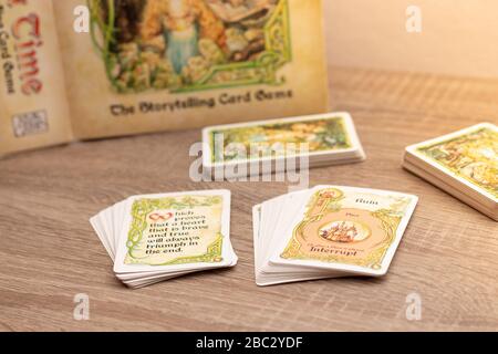 "Einmal pro Zeit", Geschichtenerspiel für bis zu sechs Spieler. Mehrere Kartendecks auf einem Holztisch. Wortruine im Fokus Stockfoto