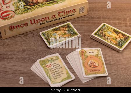 "Once Upon a Time", Geschichtenerspiel für bis zu sechs Spieler. Mehrere Kartendecks auf einem Holztisch außerhalb des Fokus, Spieltitel im Fokus, höher V Stockfoto