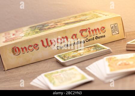 "Once Upon a Time", Geschichtenerspiel für bis zu sechs Spieler. Mehrere Kartendecks auf einem Holztisch außerhalb des Fokus, Spieltitel im Fokus Stockfoto