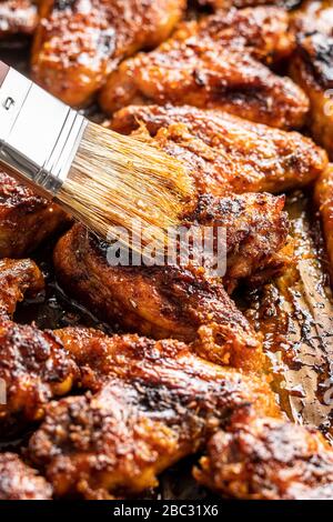 Gegrillte Hühnerflügel in Grillsauce und Pinsel. Stockfoto