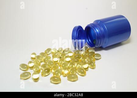 Blaue Flasche Vitamin Kapseln Omega 3 Fischöl mit etwas Auslaufen auf weißen Vordergrund Stockfoto