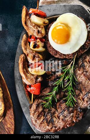 Grillplatte auf einem Teller mit gegrilltem Gemüse, gegrilltem Fleisch. Food Foto, dunkler Hintergrund Stockfoto