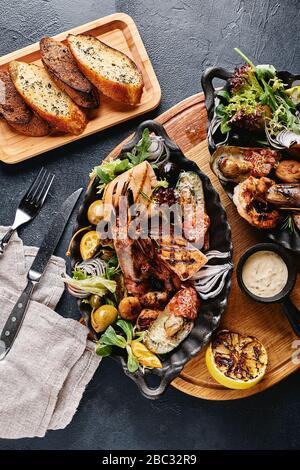 Verschiedene Meeresfrüchte auf Teller. Schöne Komposition auf einem Tisch mit Meeresfrüchten, Tintenfisch, Garnelen, Lachssteak und Tintenfisch. Lebensmittelfoto, niedrige Tonart, traditionell Stockfoto