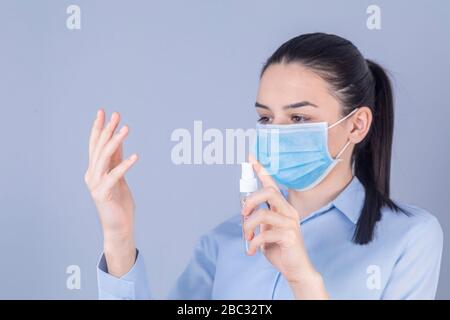 COVID-19 Pandemie-Coronavirus. Mädchen mit Schutzmaske Verholzung Alkoholspray Reinigung schützen Krankheit Kovid 19. Antiseptikum, Hygiene und Gesundheitswesen Stockfoto