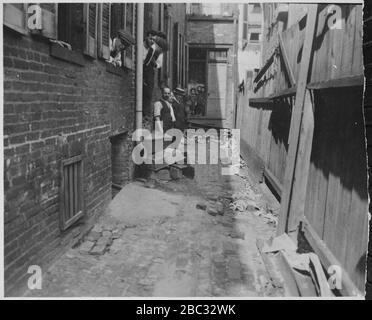 Gruppe von Mitarbeitern und mehreren kleinen Jungen in der überdachten Gasse Eingang zu einer Baltimore Garment Factory (3904010342). Stockfoto