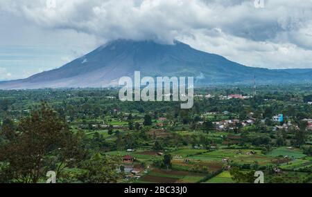 Sehr gefährlicher aktiver Sinabung-Vulkan-Berg, der aus kurzer Entfernung in der Nähe der Karo batak Hochlandfarmen von Berastagi, Nord-Sumatra, zu sehen ist Stockfoto