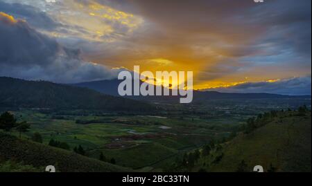 Atemberaubend lebendiger goldener Sonnenuntergang durch die Berge im karo-batak-Hochland in der Nähe des Toba-Sees, Nord-Sumatra, Indonesien Stockfoto