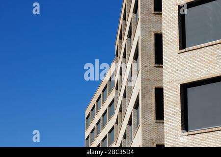 Außenansicht eines modernen mehrstöckigen Bürogebäudes mit großen Fenstern, die in einer Ziegelsteinfassade eingefasst sind. Stockfoto