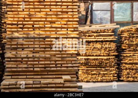 Lagerhaus zum Sägen von Bretter in einem Sägewerk im Freien. Holzmühle, Sägewerk. Lagerung von Holzbrettern. Holztafeln im Sägewerk Stockfoto