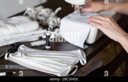 Weibliche Freiwillige nähen zu Hause schützende Antivirenmasken auf einer Nähmaschine Stockfoto