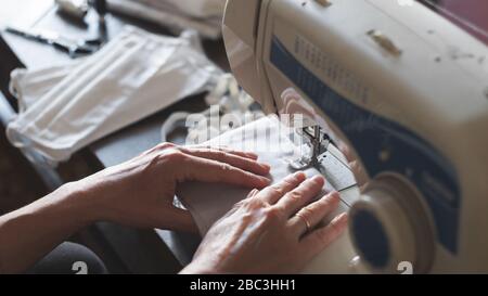 Bleiben Sie zu Hause. Antivirus Schutzmasken nähen. Frau näht Masken auf einer Nähmaschine Stockfoto