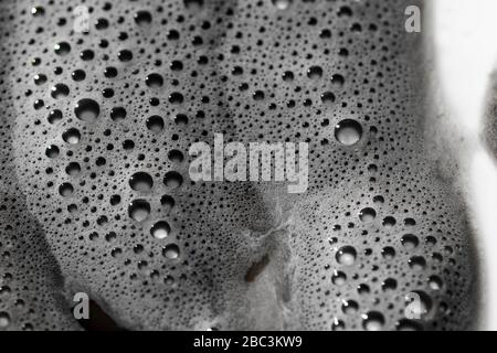 Blasenstruktur Nahaufnahme schaumig Schaum Flüssigkeit Nahaufnahme. Kohlensäurehaltiges Tau mit kleinem Blasenmuster. Schmutzige schwarze Flüssigkeit suds Makroansicht. Stockfoto