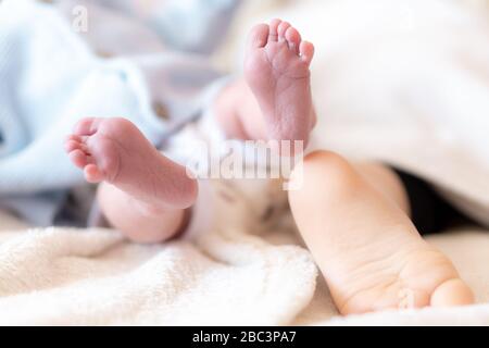 Nahaufnahme des Fußes eines neugeborenen Babys und eines einjährigen Babys. Füße von Säuglingen unterschiedlichen Alters schlafen. Fuß eines Neugeborenen über den Fuß eines anderen Stockfoto