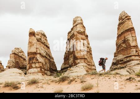 Wanderer mit Rucksack Spaziergänge neben roten Sandsteintürmen in utah Wüste Stockfoto