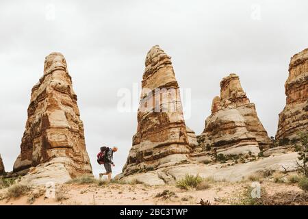 Männliche Wanderer wandern neben roten Felsen Türme in der Wüste von utah Stockfoto