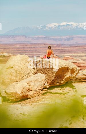 Weibliche Wanderer in Sport-BH ruht auf großen Felsen mit Blick auf canyonlands Stockfoto