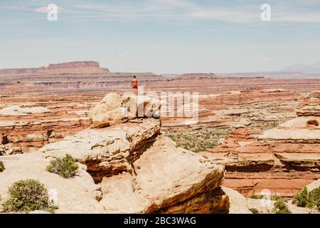 Wanderfrau nimmt in der Ansicht auf einem Vorsprung mit Blick auf das Labyrinth utah Stockfoto