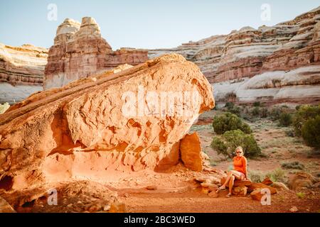 Frau sitzt auf epischen Campingplatz unter roten Felsen im Labyrinth utah Stockfoto