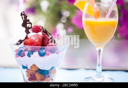 Frischer Obstsalat mit Eiscreme in Tasse auf farbenfrohem Hintergrund Stockfoto
