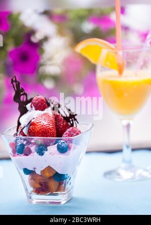 Frischer Obstsalat mit Eiscreme in Tasse auf farbenfrohem Hintergrund Stockfoto