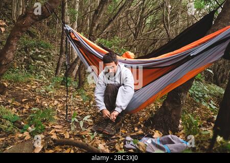 Ein Mann bereitet sich auf eine Wanderung in einer Hängematte im Wald Stockfoto