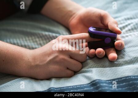 Nahaufnahme einer Person, die ein Pulsoximeter auf ihren Finger legt. Stockfoto