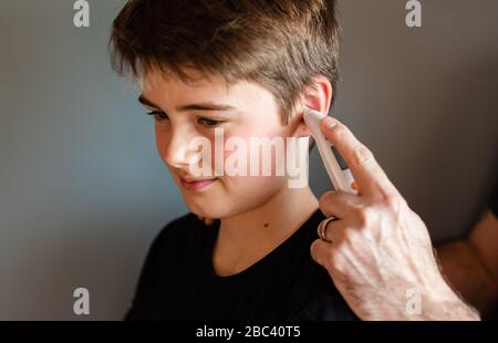 Zwischen Jungen bekommen Temperatur mit einem Ohrthermometer genommen. Stockfoto